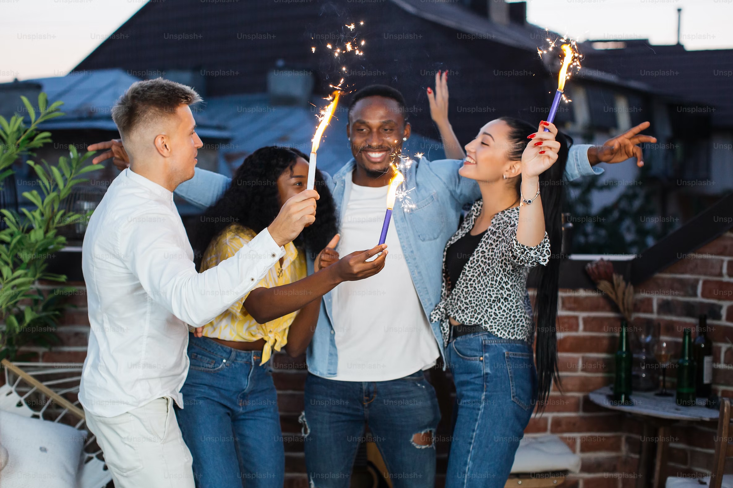 Group of friends celebrating on a rooftop with fireworks