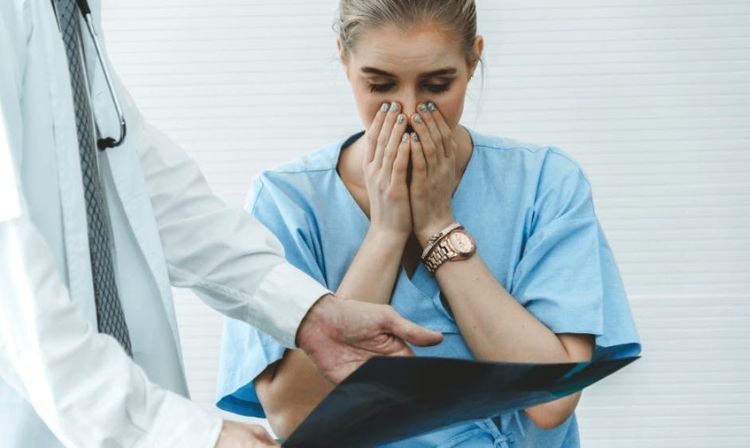 woman looking shocked while reviewing x-ray with medical practitioner 