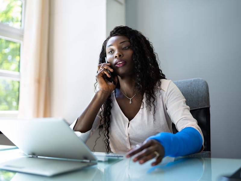 woman with an injured arm on the phone with her attorney