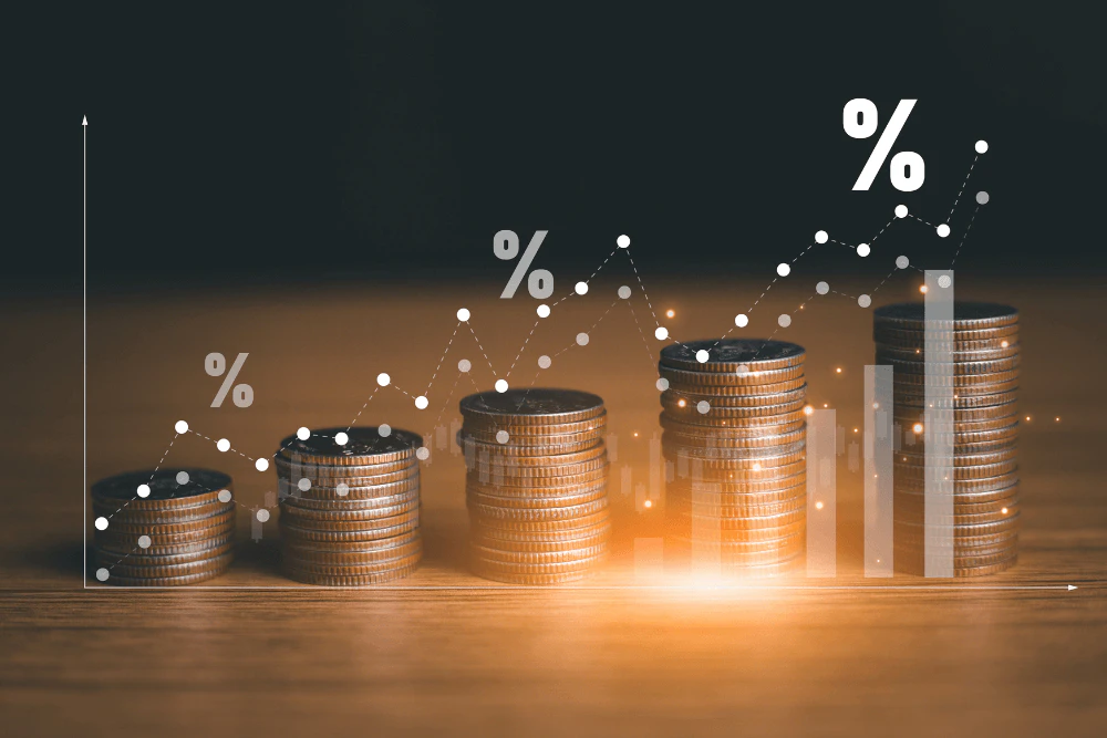 image of coins stacked up on desk with percentage signs imposed over a line graph
