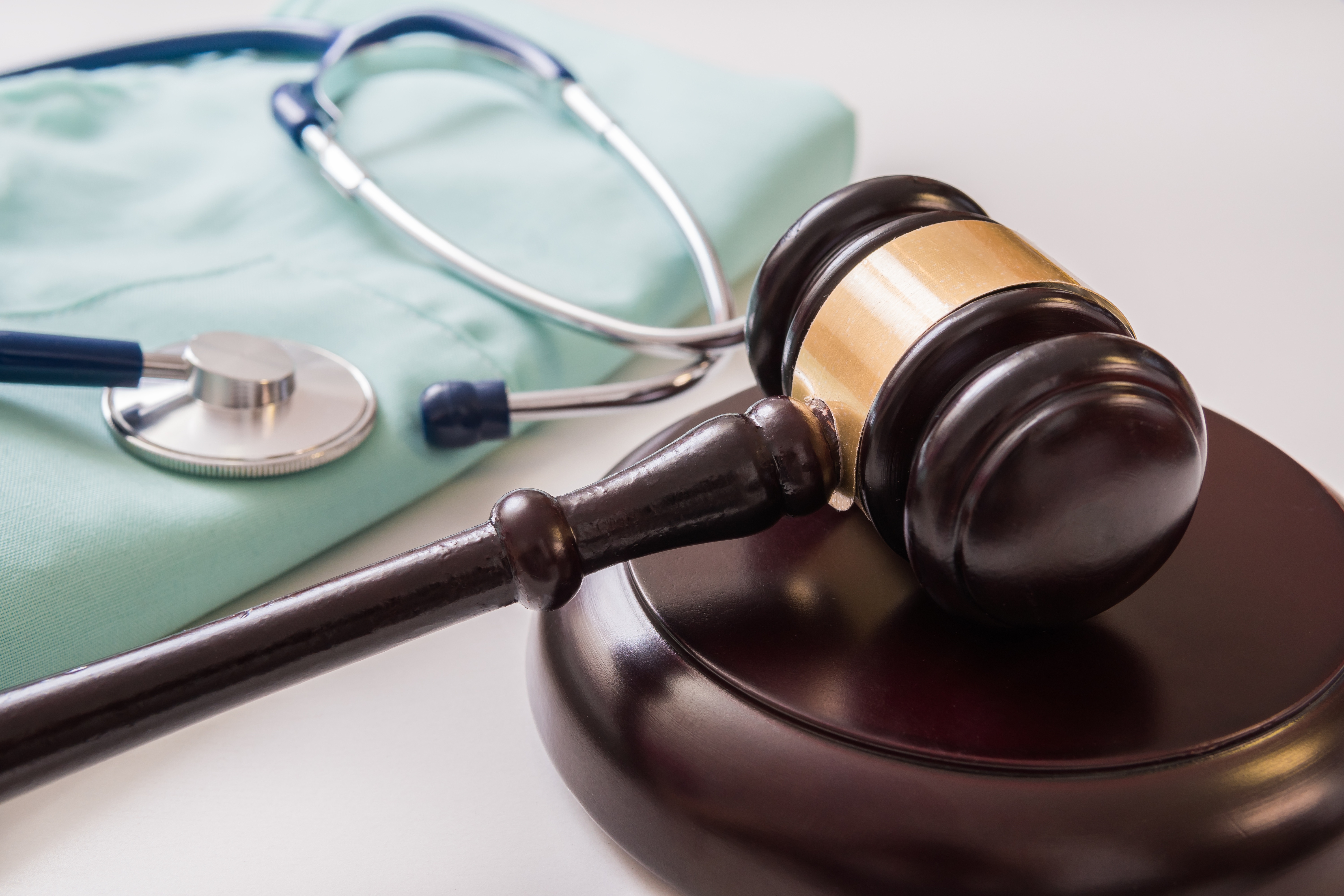 Judges gavel next to a doctors scrubs and stethoscope