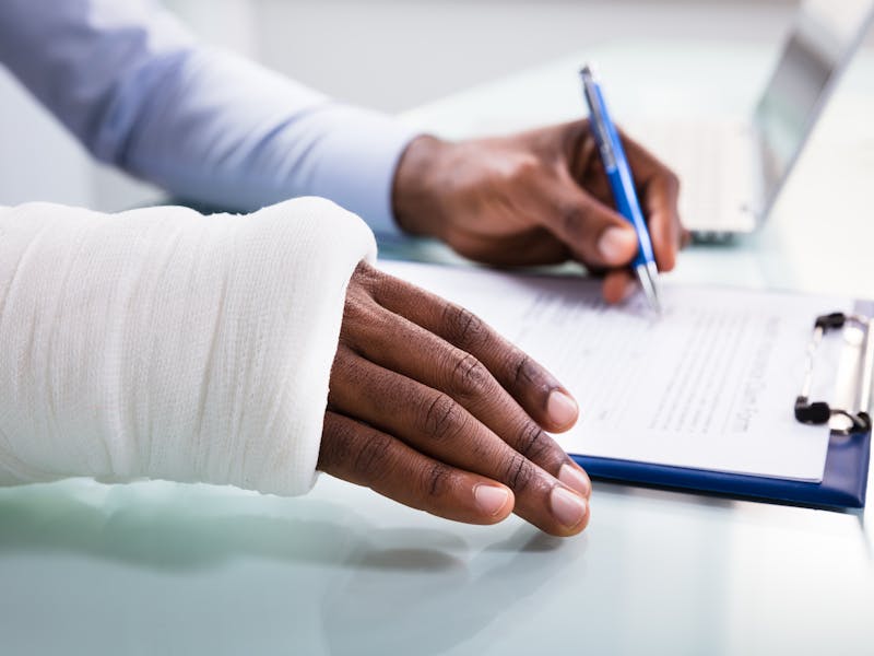 person filling out document with cast on one hand