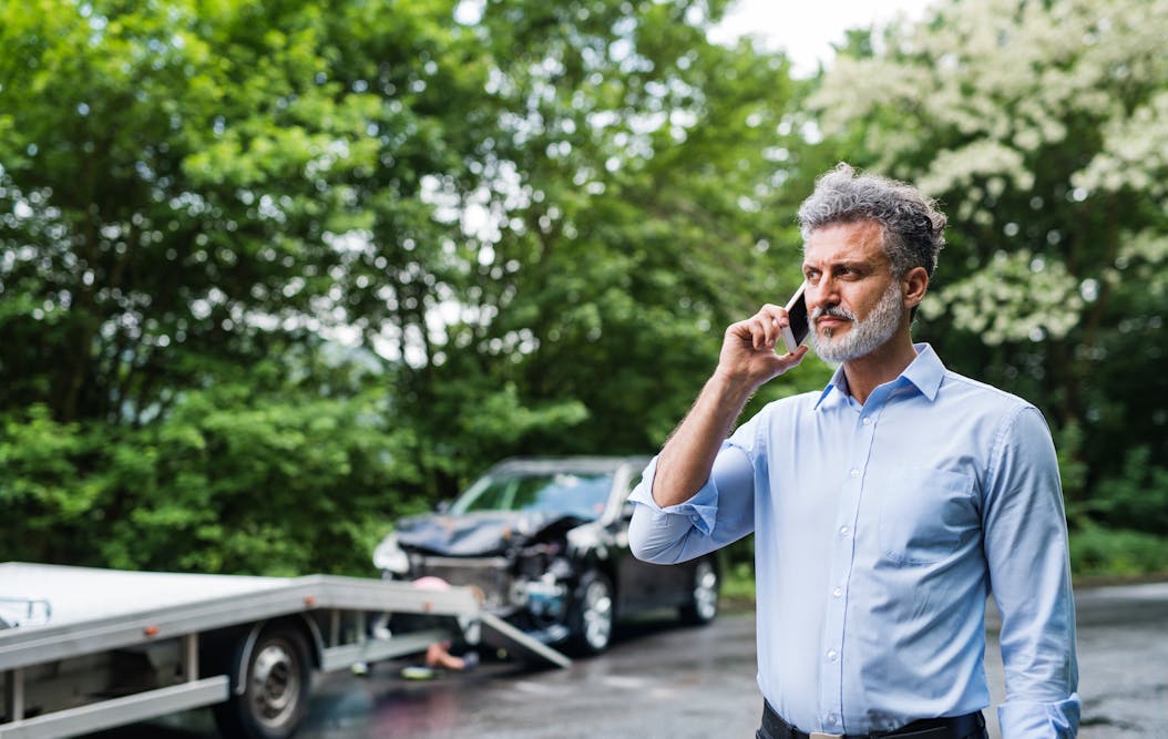 man calling emergency services after an auto accident